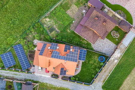 Aerial top view of new modern residential house cottage with blue shiny solar photo voltaic panels system on roof. Renewable ecological green energy production concept.の写真素材