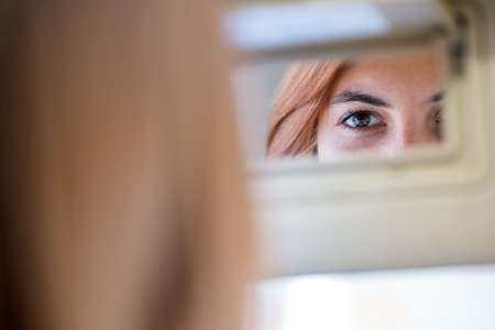 Young woman driver checking rear view mirror looking backwards while driving a car.の写真素材