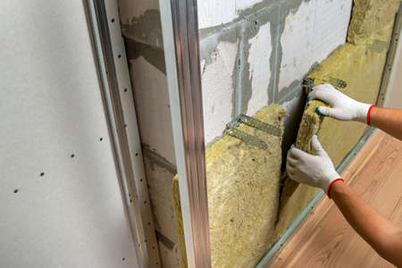 Worker insulating a room wall with mineral rock wool thermal insulation.の写真素材