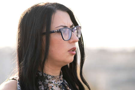 Portrait of a happy black haired woman in fashionable glasses on warm summer day outdoors.