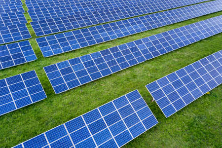 Surface of solar photo voltaic panels system producing renewable clean energy on green grass...