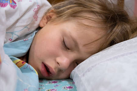 Close up of a face of pretty little child girl with slightly open mouth and scattered around hair...