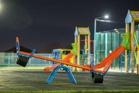 Seesaw swing in preschool yard with soft rubber flooring at night.の写真素材