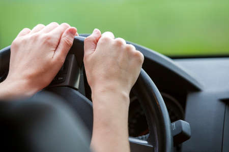 Woman hands on steering wheel driving a car.