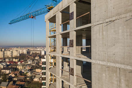 Aerial view of concrete frame of tall apartment building under construction in a city.