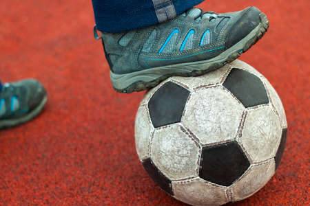 Human foot in a dirty sneaker on an old soccer ball.の写真素材