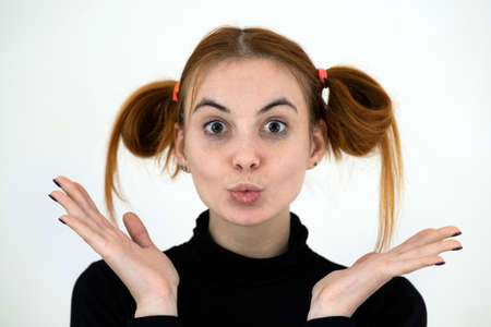 Closeup portrait of a funny redhead teenage girl with childish hairstyle isolated on white...