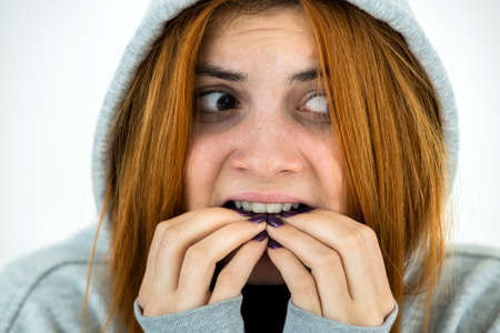 Close up portrait of scared young redhead woman wearing warm hoodie pullover.