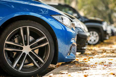 Modern cars parked on city street side in residential discrict. Shiny vehicles parked by the curb....
