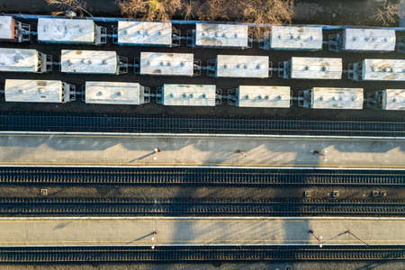Top down aerial view of many cargo train cars on railway tracks.