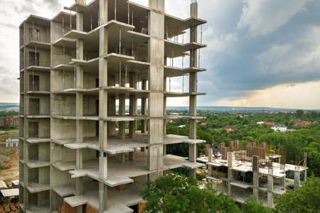 Aerial view of tower lifting crane and concrete frame of tall apartment residential building under...