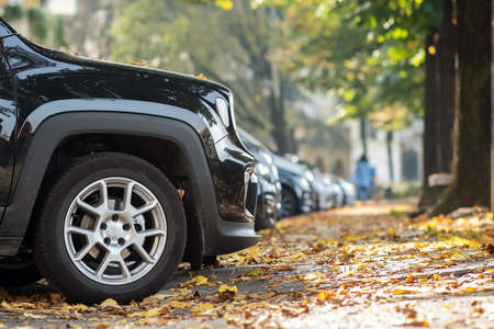 Modern cars parked on city street side in residential discrict. Shiny vehicles parked by the curb. Urban transportation infrastructure concept.の写真素材