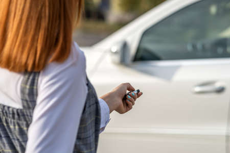 Redhead girl unlocking a car with wireless key.