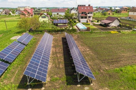 Blue solar photo voltaic panels mounted on metal frame standing on ground with green grass in field.の写真素材