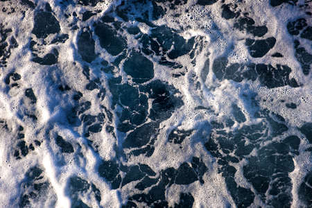 Top down aerial view of sea water surface. White foam waves texture as natural background.