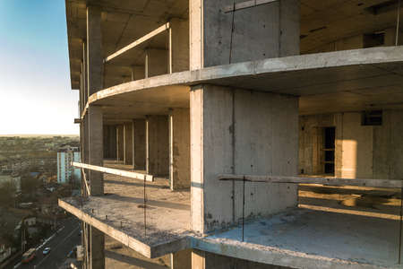 Aerial view of concrete frame of tall apartment building under construction in a city.