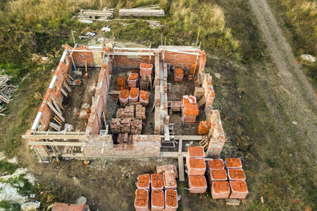 Aerial view of building site for future brick house, concrete foundation floor and stacks of yellow clay bricks for construction.の写真素材