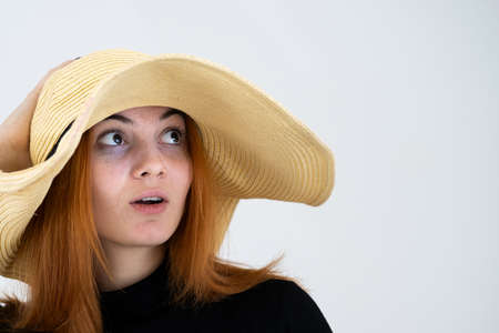 Portrait of funny redhead woman in bag yellow straw hat.