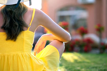 Young woman relaxing outdoors on sunny summer day. Happy lady sitting on green grass lawn daydreaming thinking. Calm girl enjoying fresh air relaxing and meditating.の写真素材