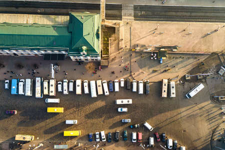 Aerial view of many cars and buses moving on a busy city street in front of railway station building...