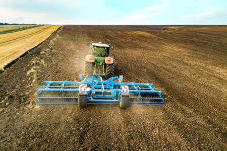 Aerial view of a tractor plowing black agriculture farm field after harvesting in late autumn.の写真素材