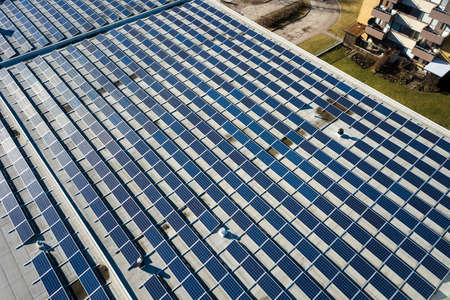 Aerial view of many photo voltaic solar panels mounted of industrial building roof.の写真素材