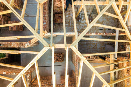 Aerial view of unfinished brick house with wooden roof structure under construction.の写真素材