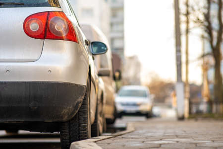 Modern cars parked on city street side in residential discrict. Shiny vehicles parked by the curb. Urban transportation infrastructure concept.の写真素材