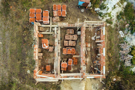 Aerial view of building site for future brick house, concrete foundation floor and stacks of yellow clay bricks for construction.の写真素材