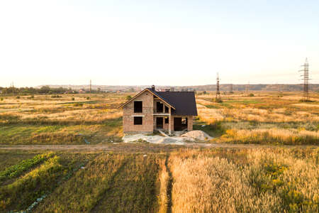 Unfinished brick house with wooden roof structure covered with metal tile sheets under construction.の写真素材
