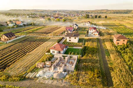 Top down aerial view of two private houses, one under construction with concrete foundament and...