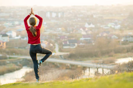 Young woman standing outdoors enjoying city view. Relaxing, freedom and wellness concept.の写真素材