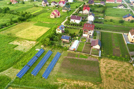 Aerial view of a private house in summer with blue solar photo voltaic panels on roof top and in the...