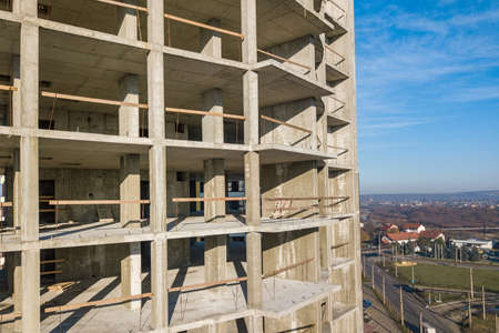 Aerial view of concrete frame of tall apartment building under construction in a city.