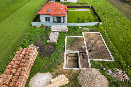 Aerial view of building site for future brick house, concrete foundation floor and stacks of yellow clay bricks for construction.のeditorial素材
