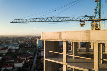Aerial view of concrete frame of tall apartment building under construction in a city.