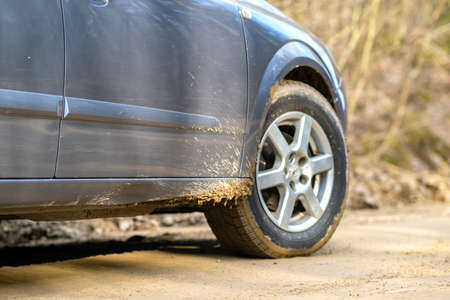 Close up of dirty car wheel with rubber tire covered with yellow mud.