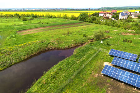 Blue solar photo voltaic panels mounted on metal frame standing on ground with green grass in field.