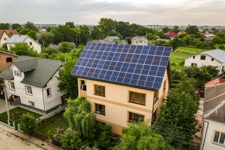 Aerial top view of new modern residential house cottage with blue shiny solar photo voltaic panels...