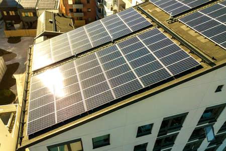 Aerial view of solar photovoltaic panels on a roof top of residential building block for producing...