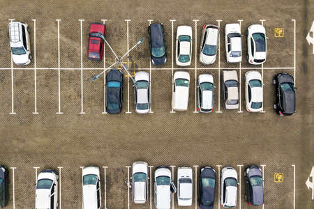 Top down aerial view of many cars on a parking lot of supermarket or on sale car dealer market.