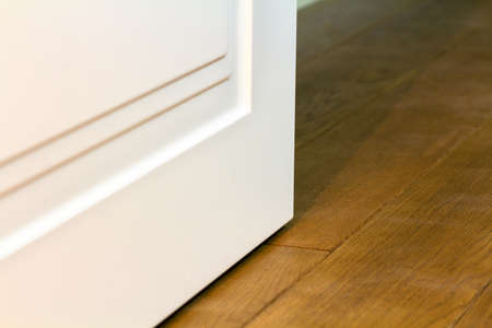 Detail of contemporary white room door on wooden yellow floor.の写真素材