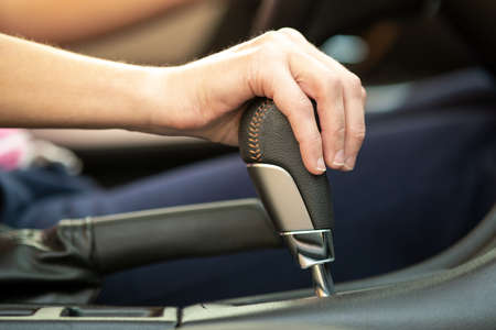 Close up of woman driver holding her hand on automatic gear shift stick driving as car.の写真素材