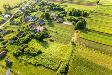 Aerial view of a small village win many houses and green agricultural fields in spring with fresh...