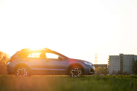 Landscape with blue off road car on green grass at sunset. Traveling by auto, adventure in wildlife, expedition or extreme travel on a SUV automobile. Offroad 4x4 vehicle in field at sunrise.の写真素材