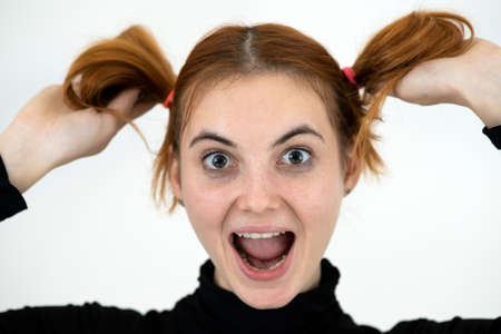 Closeup portrait of a funny redhead teenage girl with childish hairstyle isolated on white backround.の写真素材