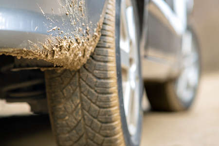 Close up of dirty car wheel with rubber tire covered with yellow mud.の写真素材