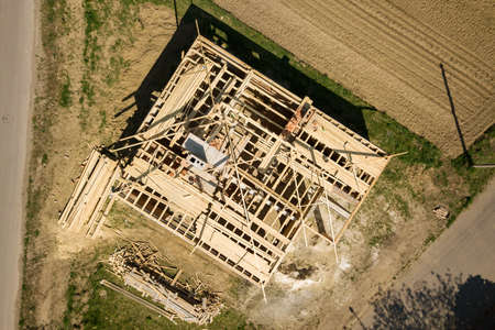 Aerial view of unfinished brick house with wooden roof frame structure under construction.の写真素材