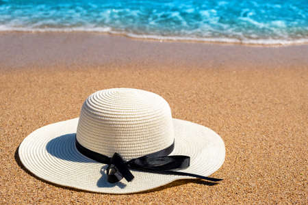 White woman straw hat laying on tropical sand beach with blue vibrant ocean water in background on sunny summer day. Vacations and destination travel concept.の写真素材