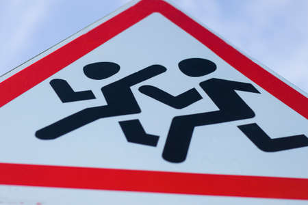 Information road sign, triangular white shield with running figures. Attention, school ahead, reduce...